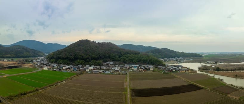 Panoramic aerial view of plowed fields by small village in Shiga, Japan. High quality photo