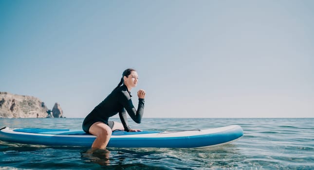 Woman sup yoga. Middle age sporty woman practising yoga pilates on paddle sup surfboard. Female stretching doing workout on sea water. Modern individual hipster outdoor summer sport activity