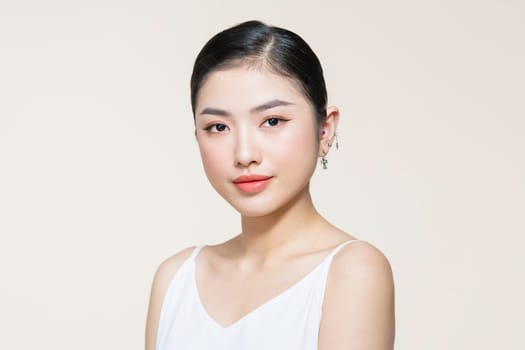 Beautiful young Asian woman with clean fresh skin on beige background