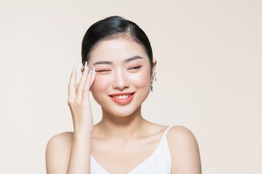 Beautiful young asian woman with clean fresh skin on beige background,