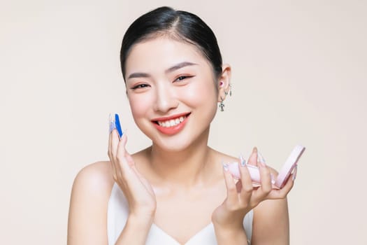Portrait of attractive young adult woman applying blusher