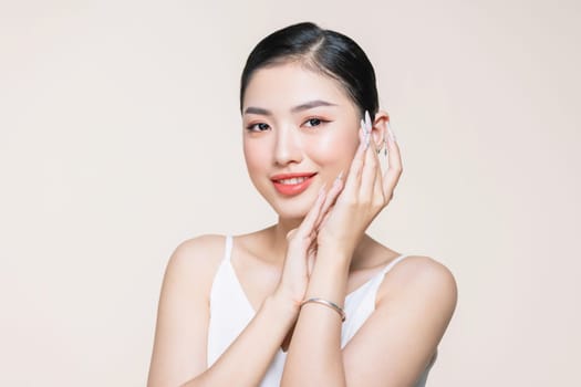 Beautiful woman face studio on beige touching face hand