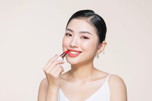 Beautiful young woman applying lipstick