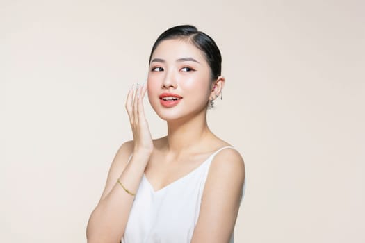 Beautiful young asian woman with clean fresh skin on beige background,