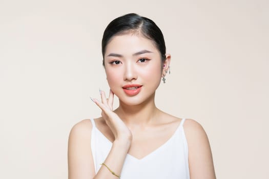 Beauty portrait of asian smiling laughing woman clean fresh face isolated on beige background