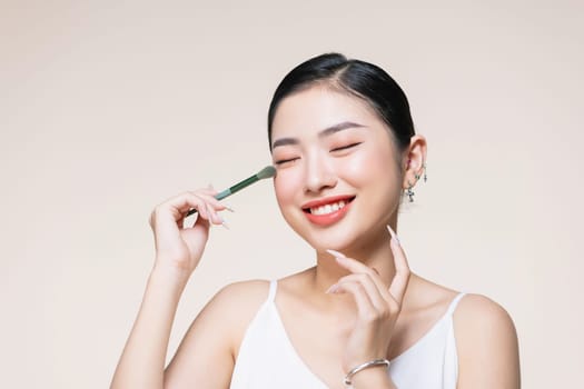 Beautiful and charming asian female applying a beautiful eyeshadow on her eyelid.