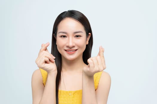 Beautiful young Asian woman shows mini heart fingers on isolated white background.