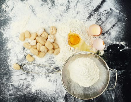 Eggs, flour and pasta for cooking in kitchen with Italian cuisine, dough recipe and dinner ingredients. Gnocchi, table top and carbs on dark background for healthy eating, yellow color and lunch food.