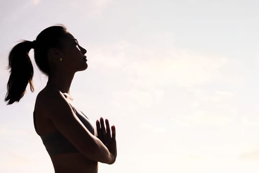 backlight portrait of young asian woman practicing yoga in pray position, concept of mental relaxation and healthy lifestyle, copy space for text