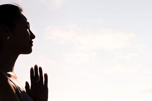 backlight portrait of young asian woman practicing yoga in pray position, concept of mental relaxation and healthy lifestyle, copy space for text