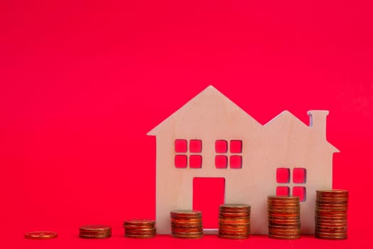 Coins and houses on a red background. The concept of the rising price of real estate