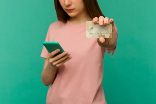 Photo of pleased happy screaming young woman posing isolated over blue wall background using mobile phone holding credit card. - image