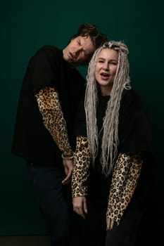 A man and a woman are standing together, smiling at the camera as they pose for a photograph. The man has his arm around the womans waist, and they both look happy and relaxed.