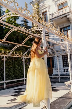 beautiful woman in a long puffy yellow dress posing near the arch.