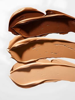Three different shades of foundation are layered on a white surface, resembling the layers of a decadent chocolate dessert