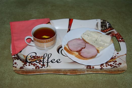 Tasty breakfast. Warm tea with sandwiches.Tea and two sandwiches with boiled pork and cheese.