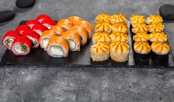 Top view sushi set. Philadelphia roll, california, unagi with fresh ingredients on black background. Sushi menu. Japanese asian food