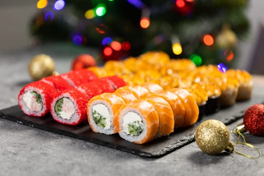 Sushi for Christmas New Year party, winter holiday food delivery menu. Sushi set asian food in background Christmas tree with festive garland