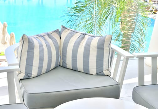 lounge with striped sofas against the backdrop of pool of water
