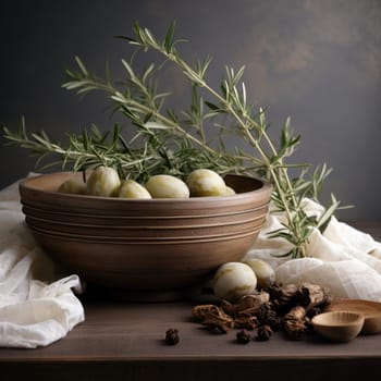A bowl filled with olives, garnished with a sprig of fresh rosemary, resting on a table.