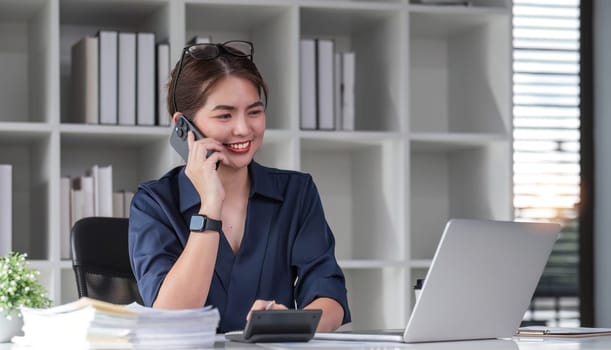 Young accountants use phones and calculators to calculate taxes and manage business accounts in the office..