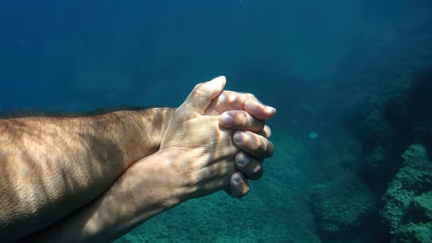 A man and woman crossed human hands underwater detail
