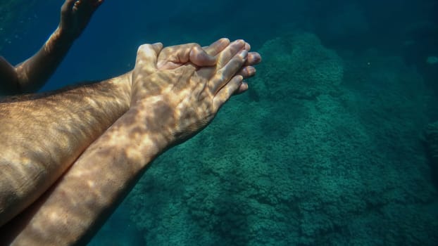 A man and woman crossed human hands underwater detail