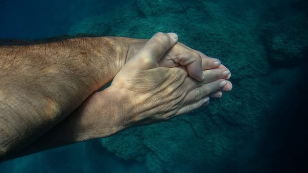 A man and woman crossed human hands underwater detail