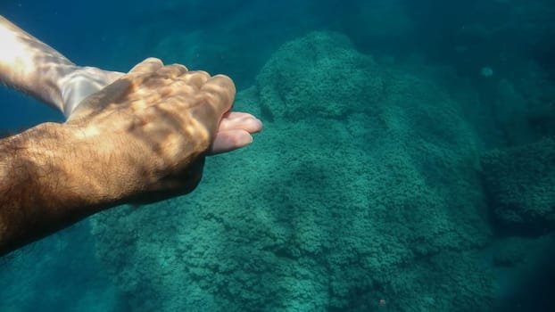 A man and woman crossed human hands underwater detail