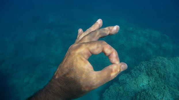 ok sign human hand underwater detail close up