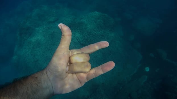 ily sign 3 fingers up human hand underwater detail close up