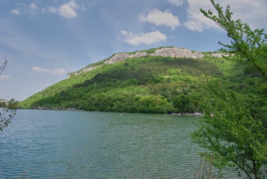 Clouds float above the mountain in two planes, the ones above are white and thick, the ones above the mountain are long, gray.