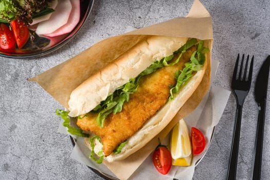 Fried fish sandwich with greens on the stone table. Turkish name Balik Ekmek