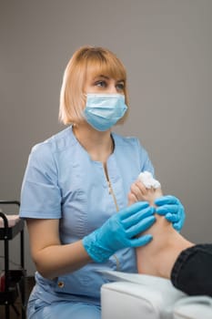 Portrait of podologist bandaging toes of a patient after podiatrist treatment.