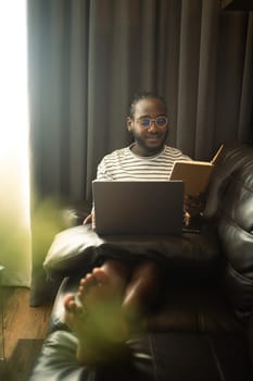 Young African American man working or browsing internet on laptop at home.