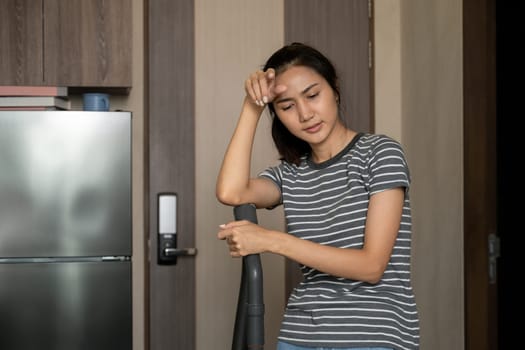 Young housewife wiping sweat on her forehead feeling exhausted after doing housework.