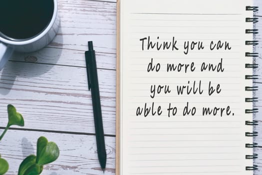 Motivational quote on notepad with pen, a cup of coffee and potted plant on wooden desk.