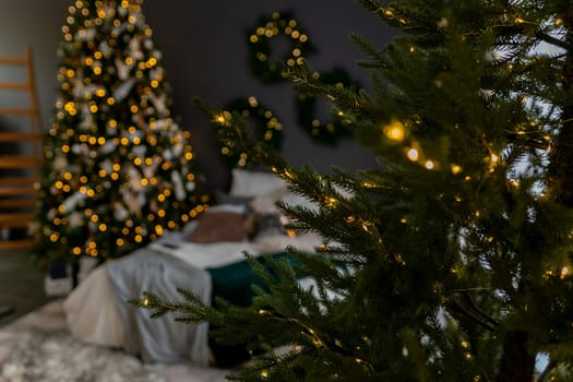 A bedroom with a Christmas tree and a bed. The bed is covered with a green comforter and pillows