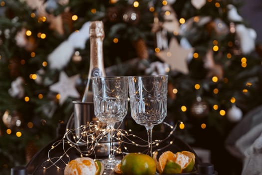 Champagne glasses, New Year decor. New Year's festive setting, family holidays.Two glasses of champagne are on the table against the background of New Year's decorated tree