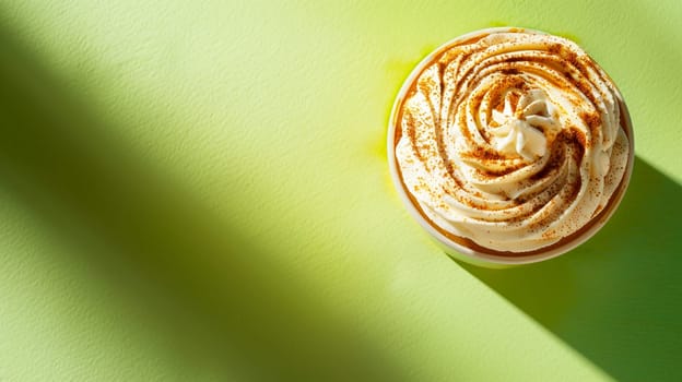 Top view of sweet cupcake with creamy frosting dusted with cinnamon, vibrant green background, dessert concept shadow play