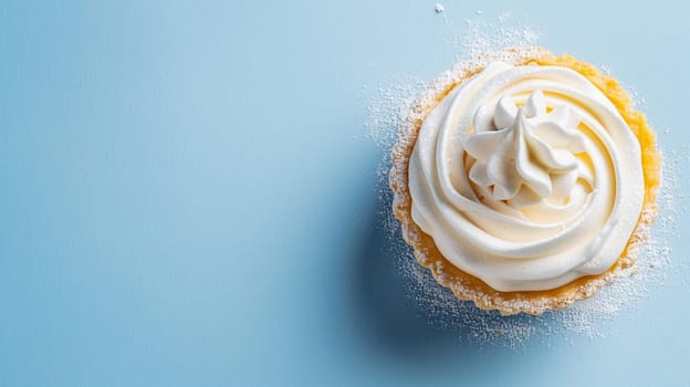 Elegant cream tart dusted with sugar captures dessert artistry. Top view showcases confection perfection on blue backdrop, inviting sweet indulgence.