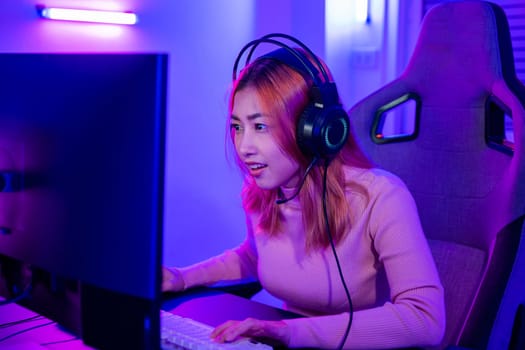 Young player woman wearing gaming headphones intend to do playing live stream games online at home, Happy Gamer endeavor plays online video games tournament with computer desktop with neon lights