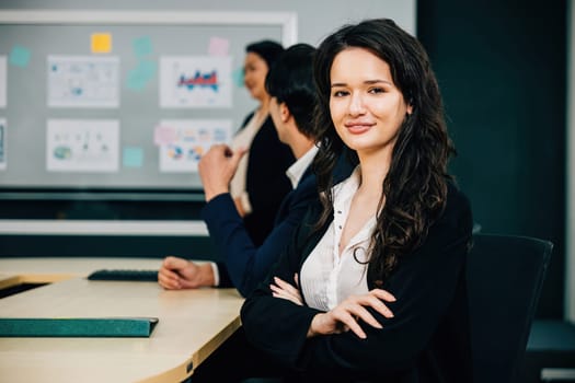 A portrait of a confident businesswoman in a vibrant meeting room. The CEO, manager, and diverse colleagues embody the essence of teamwork, strategy, and success. Workplace collaboration is thriving.