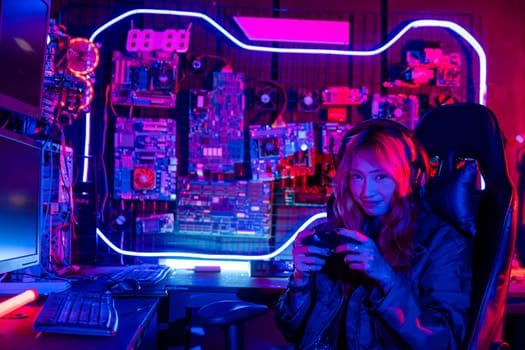 Gamer using joystick controller for virtual tournament plays online video game with computer neon lights, woman wear gaming headphones playing live stream esports games console at home