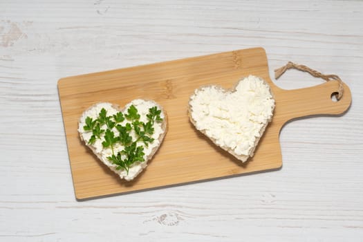 Two heart-shaped sandwiches with cottage cheese and parsley.