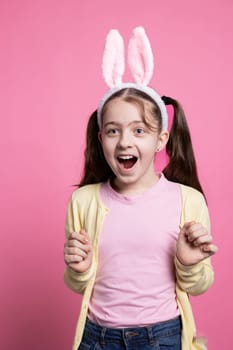 Young joyful toddler being surprised by easter festivity in studio, feeling excited about toys and celebrating spring event. Little enthusiastic kid being positive about april celebration.