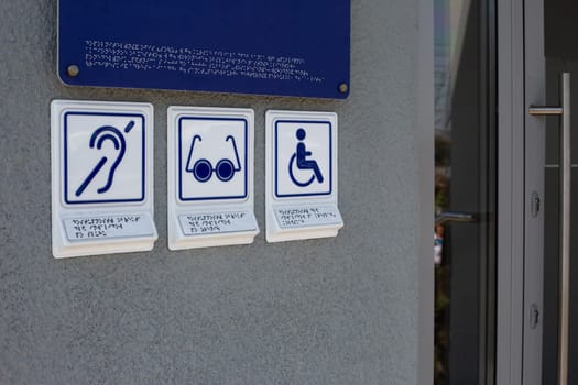 Set of symbols with braille text on special sign near the entrance to the building, accessible public environment for disabled people