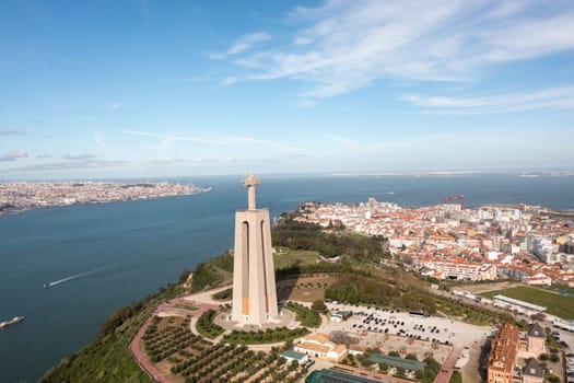 Portugal. Panoramic drone view of the Cristo Rei statue in Almada on sunny summer day. Giant monument Sanctuary of Christ the King in background city landscape and blue sky