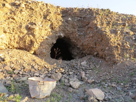 Abandoned Mine Site with Rusty Bucket in Arizona Desert. This hole in the alluvium is most likely a shelter. It is located at an old mine site in Arizona. High quality photo