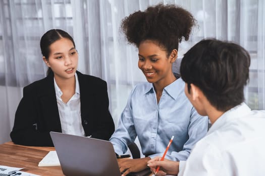 Happy diverse business people work together, discussing in corporate office. Professional and diversity teamwork discuss business plan on desk with laptop. Modern multicultural office worker. Concord